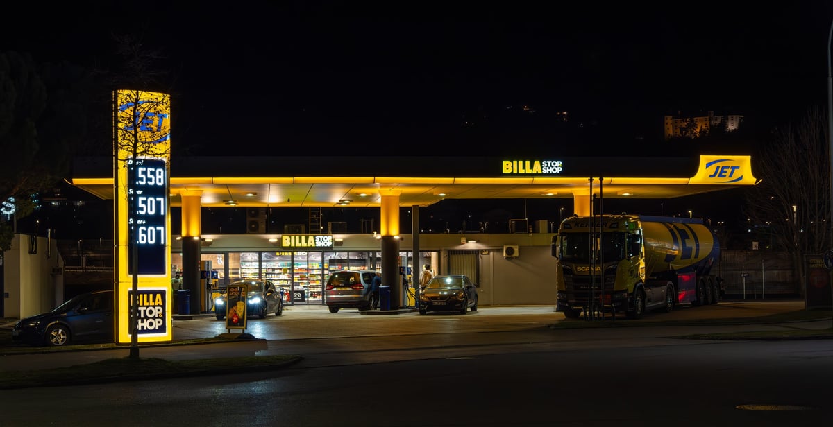Innsbruck, Austria - March 20, 2025: A brightly lit Jet gas station at night with Billa stop shop. Large illuminated sign displaying fuel prices. A fuel truck and cars
